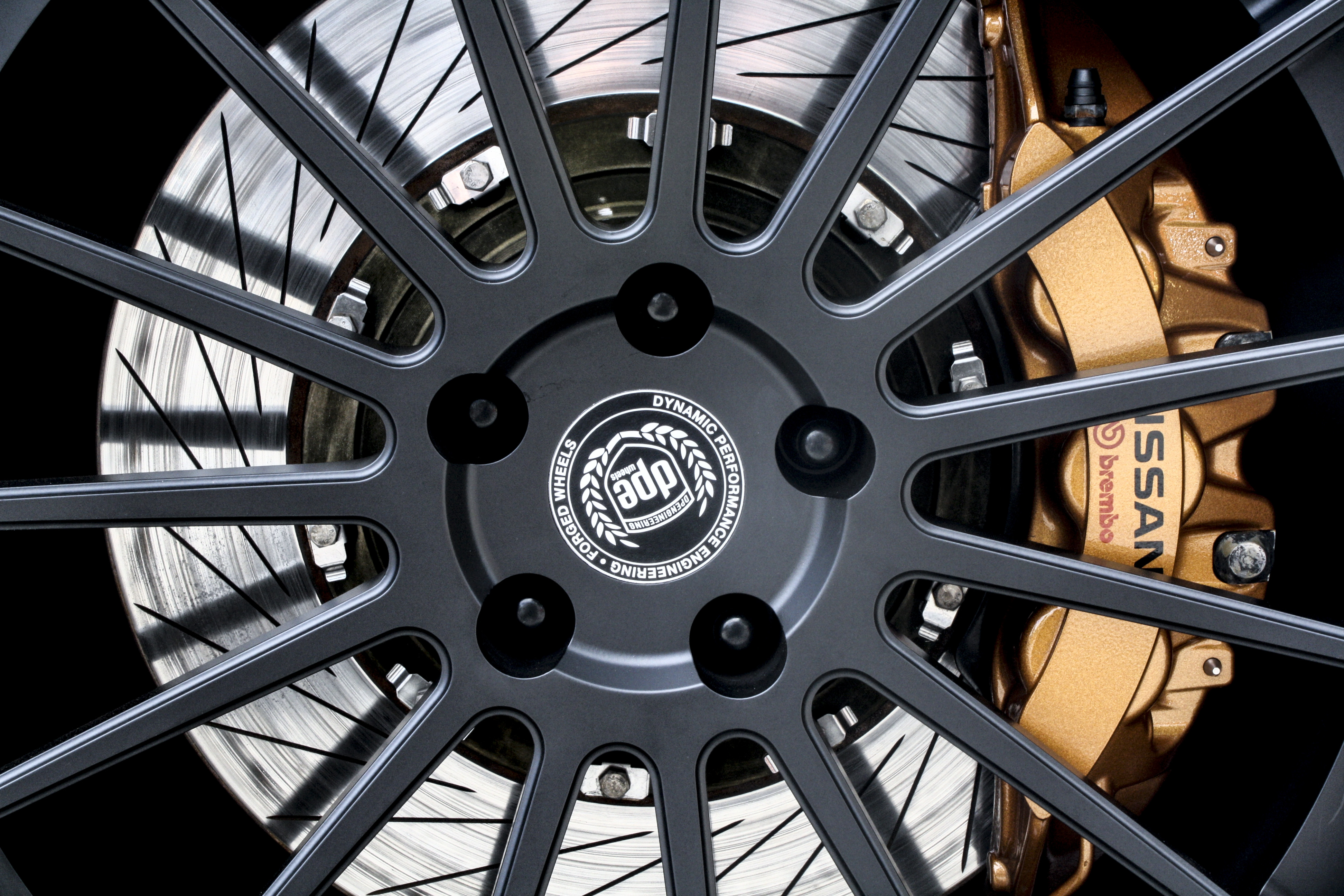 Car disc brake rotor and caliper behind a wheel